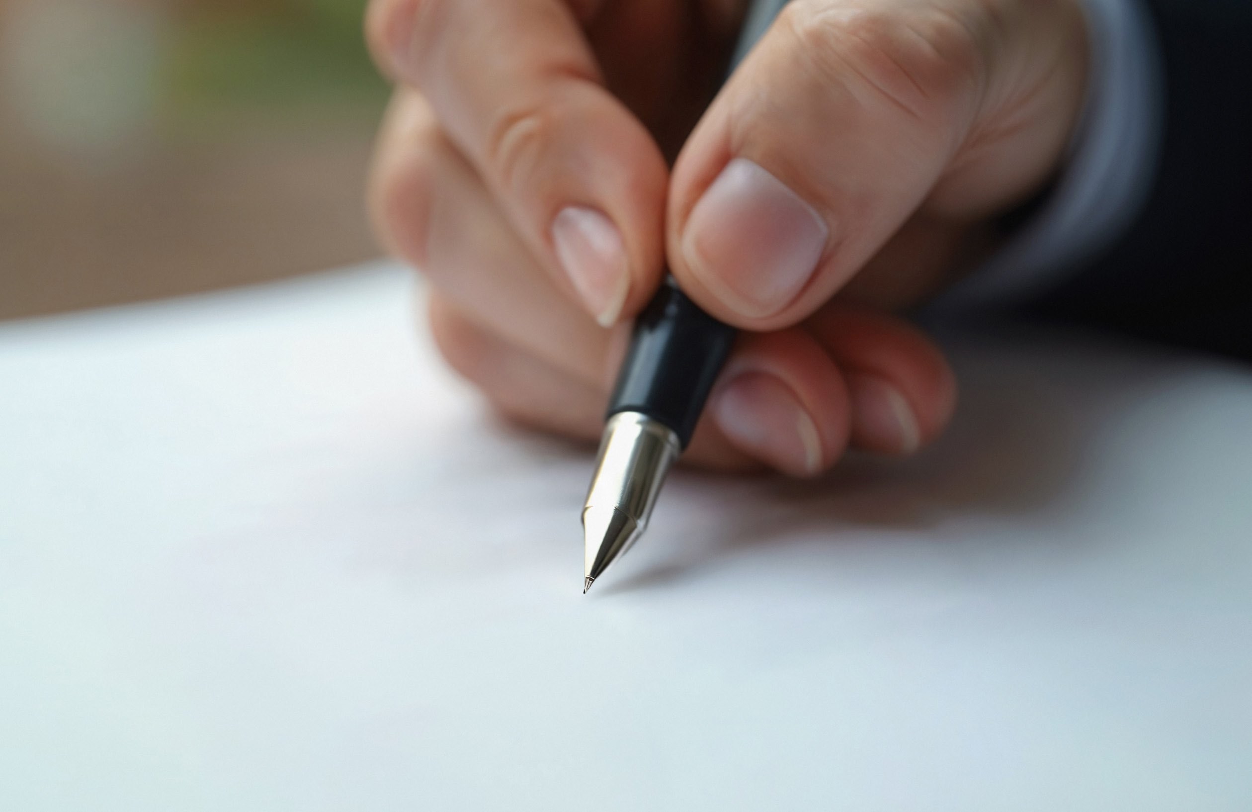 Una persona che scrive con una penna sul foglio, simbolo della scelta testamentaria